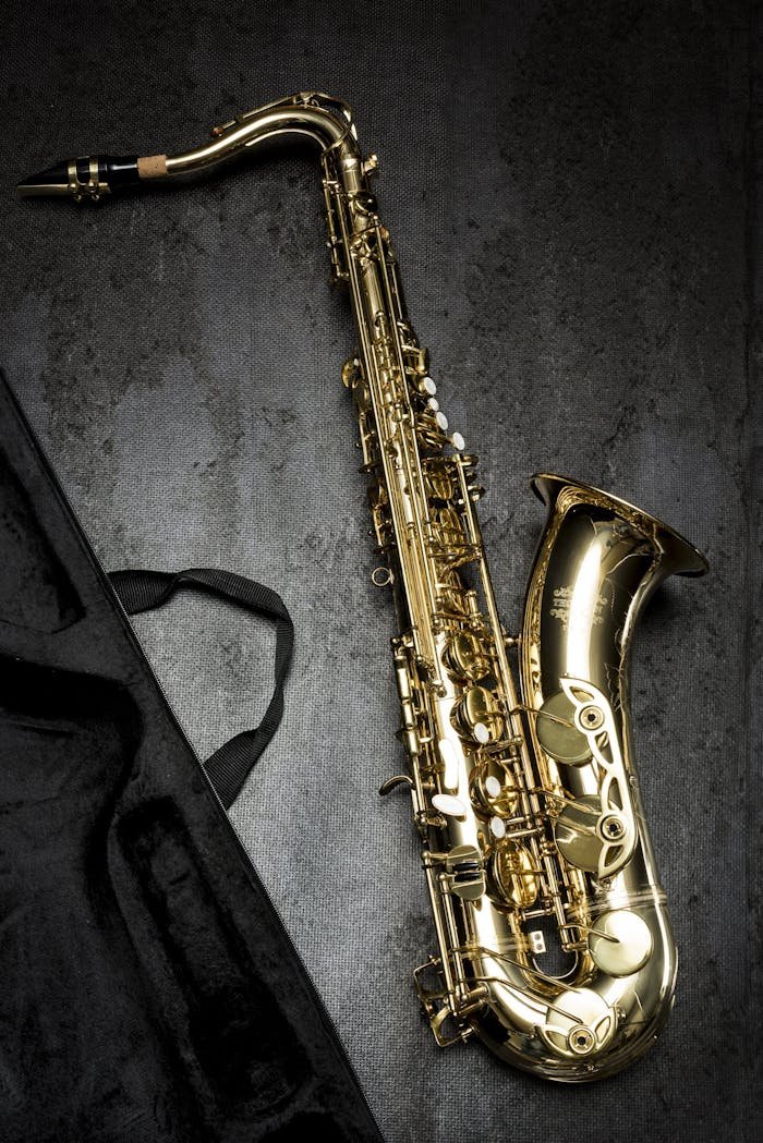 A sleek golden saxophone laid on a textured dark background, showcasing its intricate design
